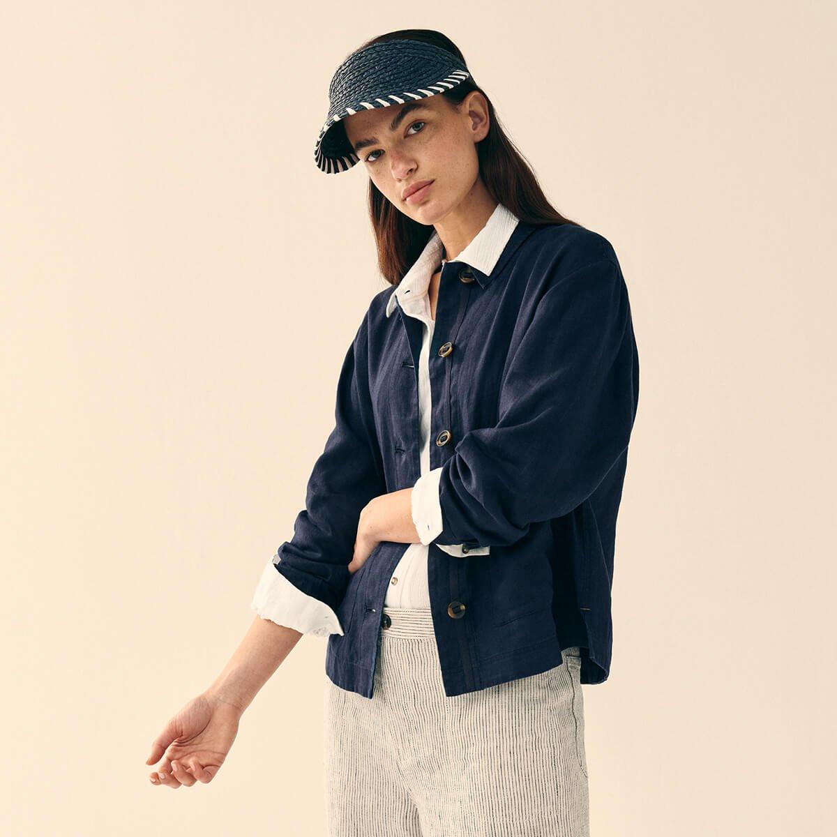 a woman in a hat and pants standing with her hands on her hips