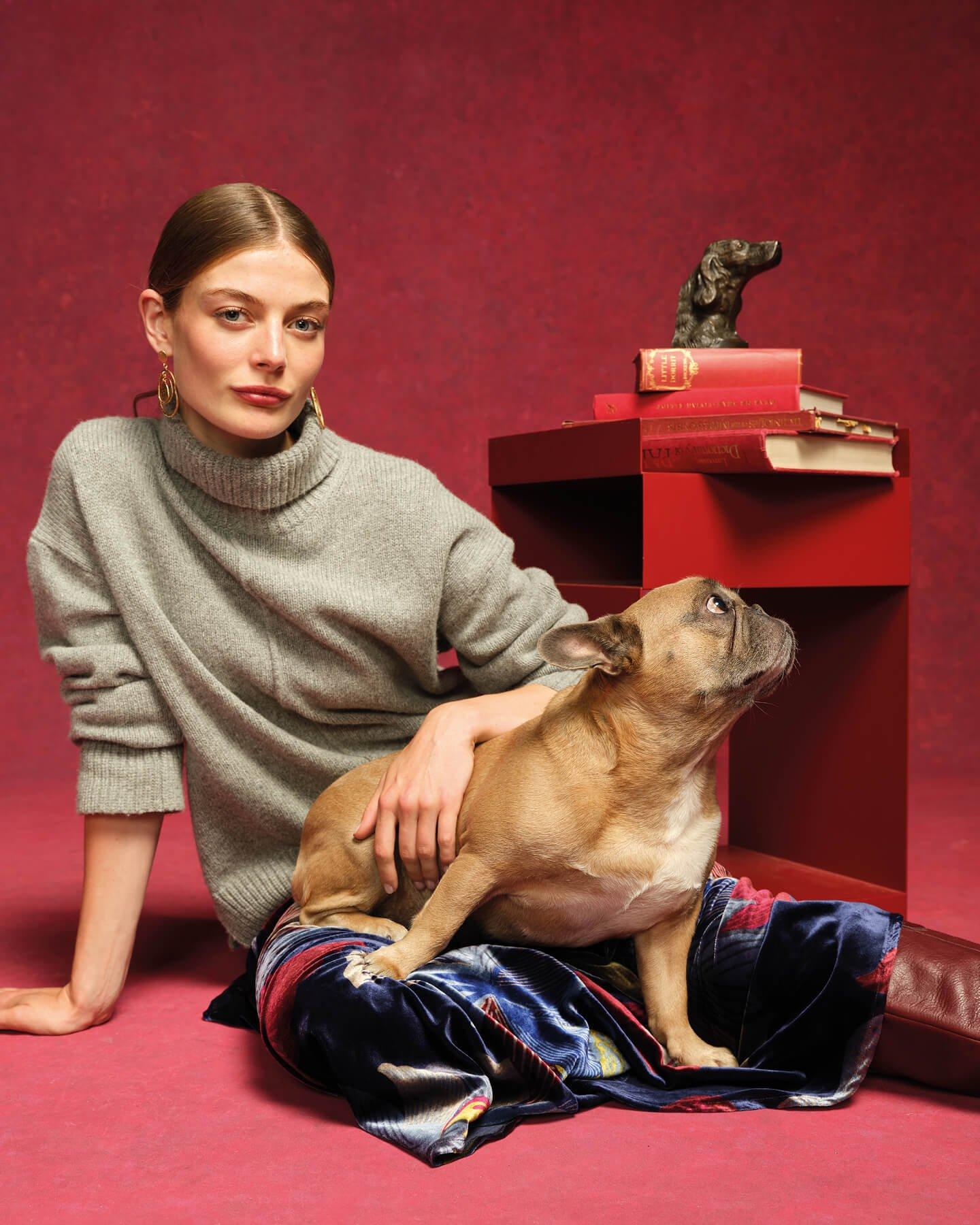 a woman sitting on a red carpet with a dog in her lap