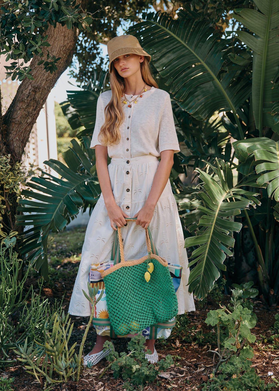 a woman in a white dress holding a green bag