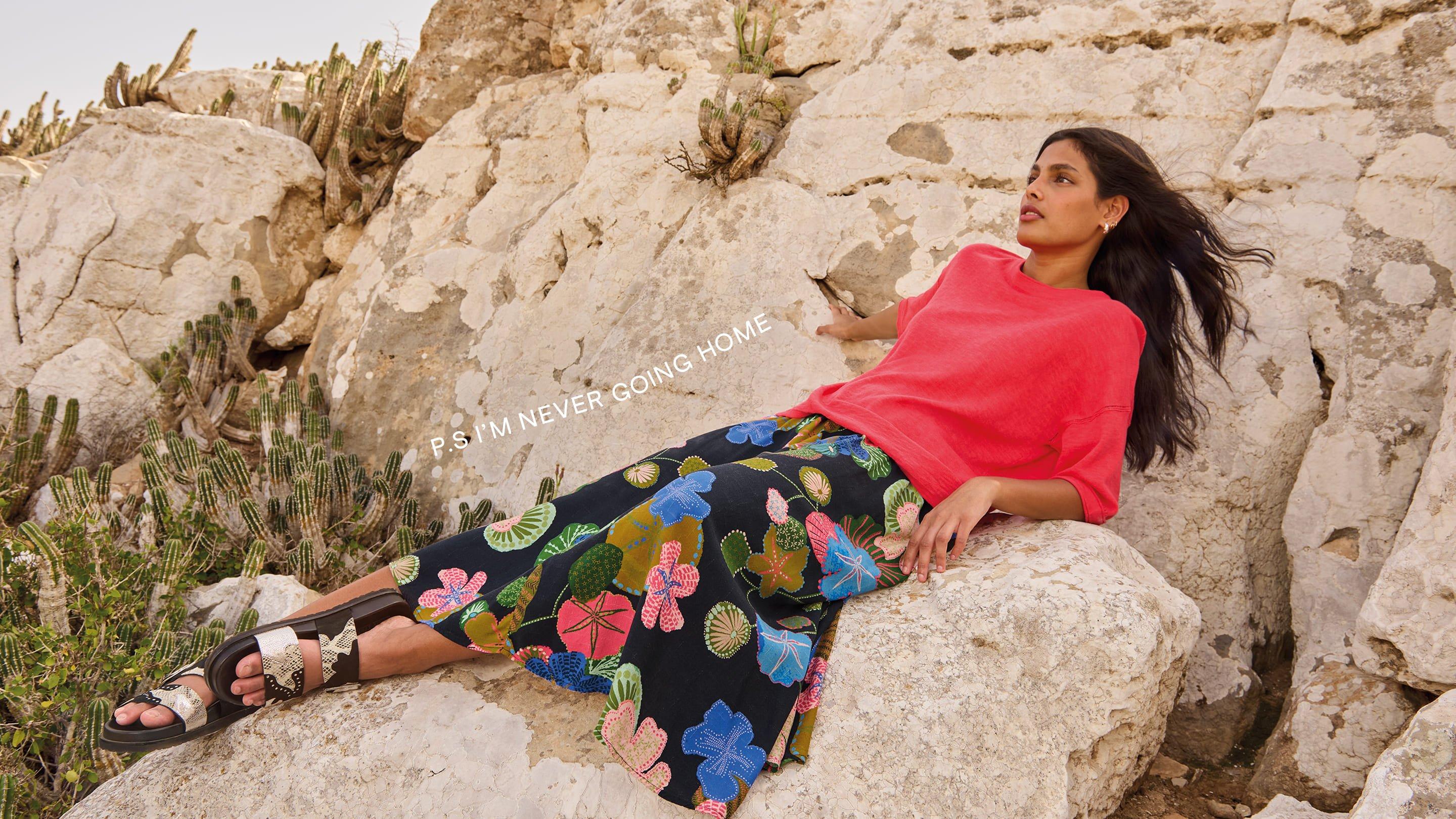 a woman laying on a rock with a flower skirt