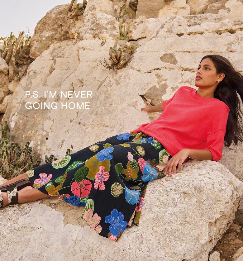 a woman laying on a rock with a flower in her hair