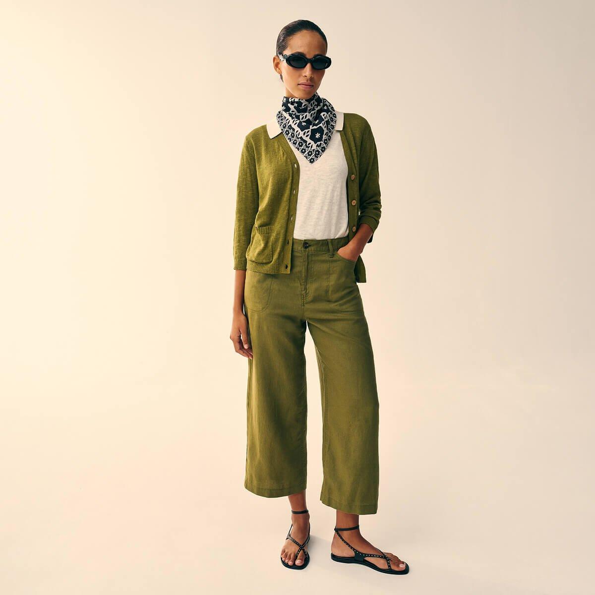 a woman in a green jacket and pants standing up