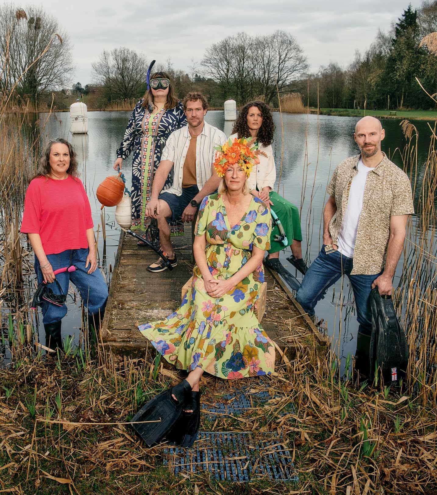 a group of people standing on a dock next to a lake