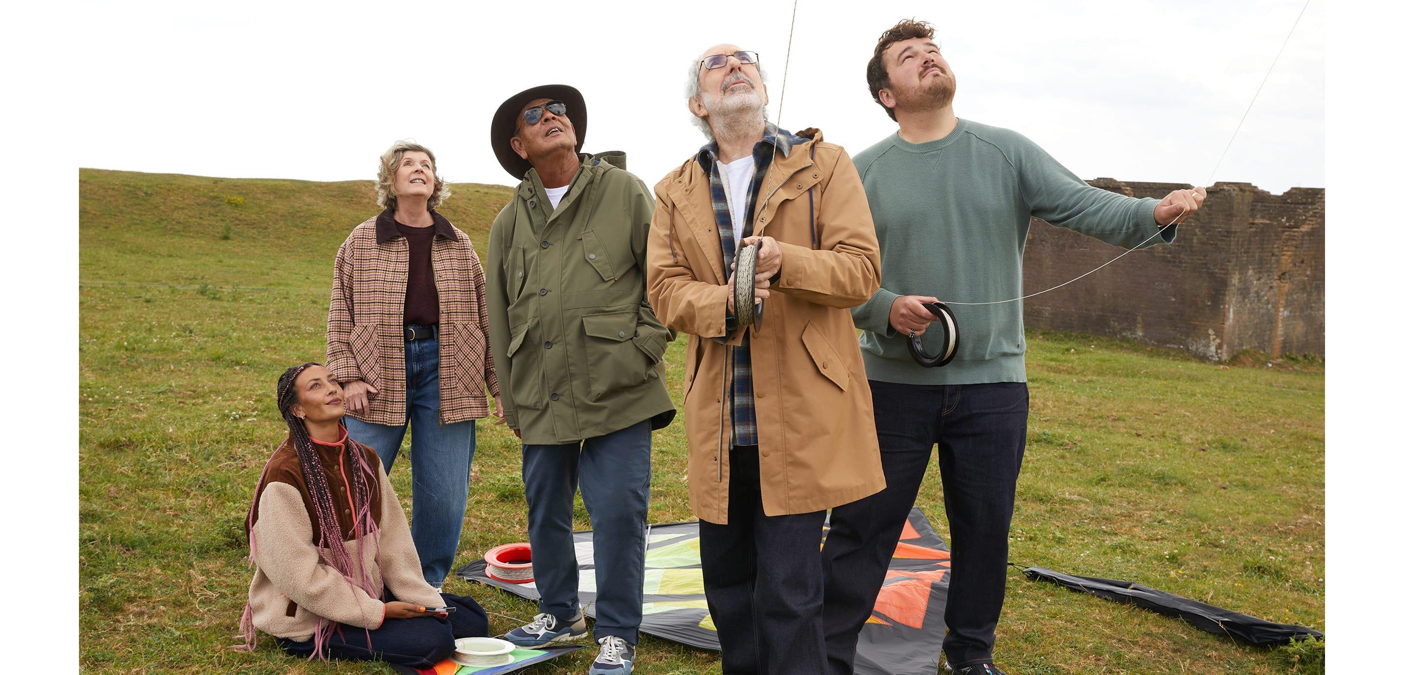 a group of people standing in a field looking up at a kite