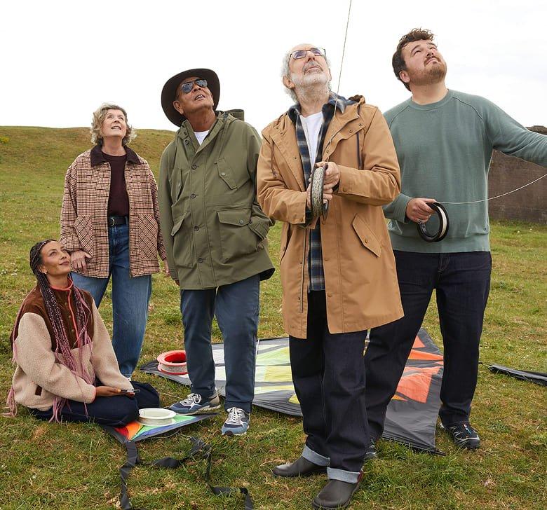 a group of people standing in a field with a kite