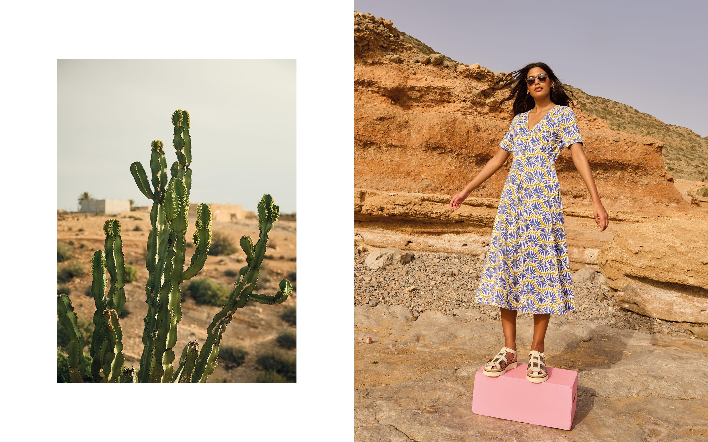 a woman in a dress standing next to a cactus
