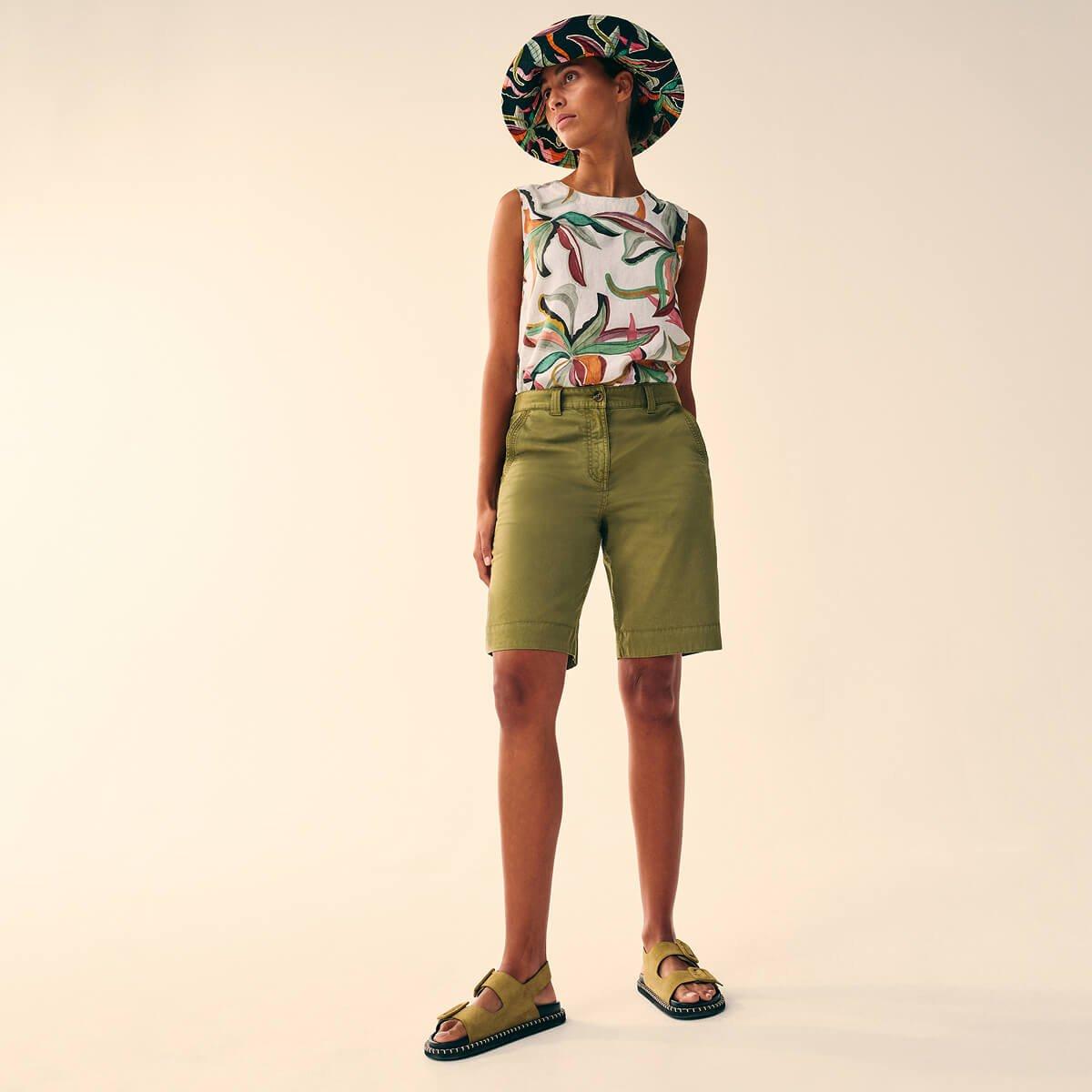 a woman in a hat and linen shorts standing up