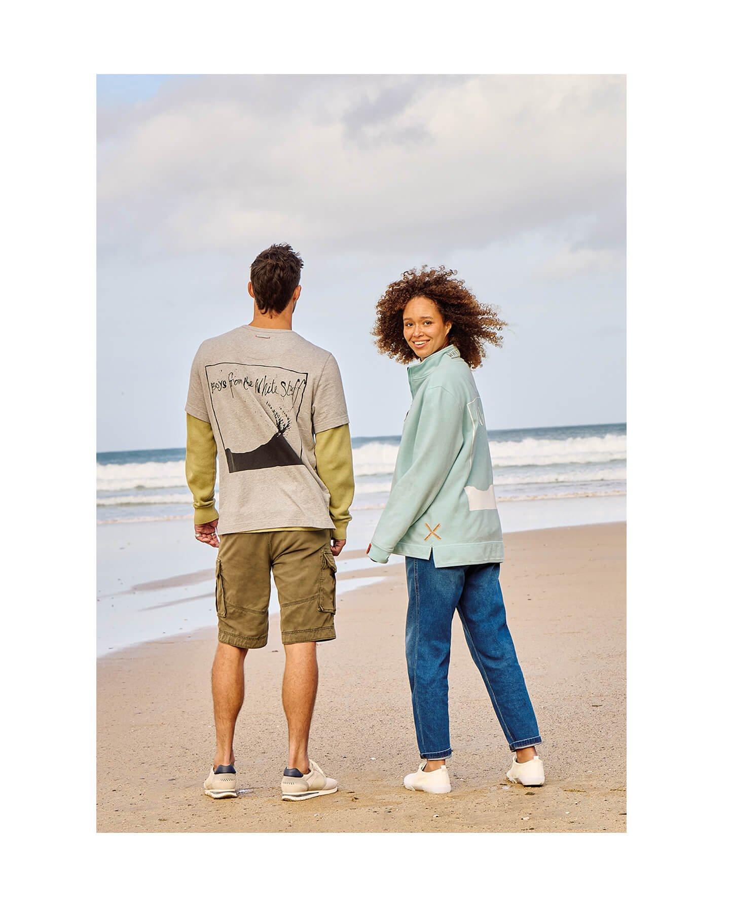 a man and woman standing on a beach holding hands