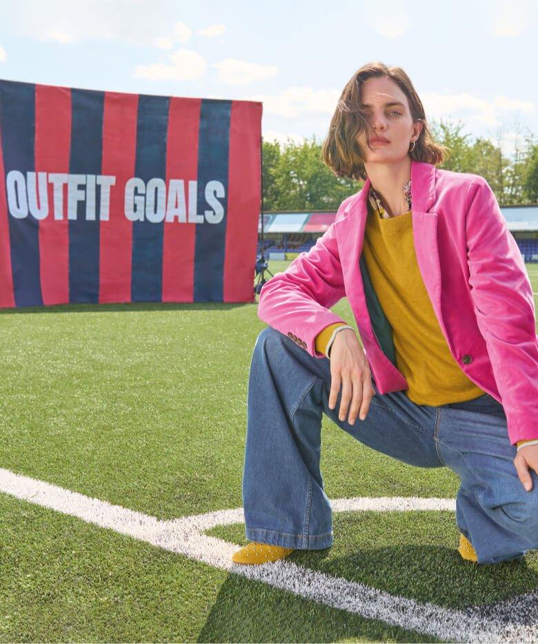 a woman in pink jacket kneeling on a football field