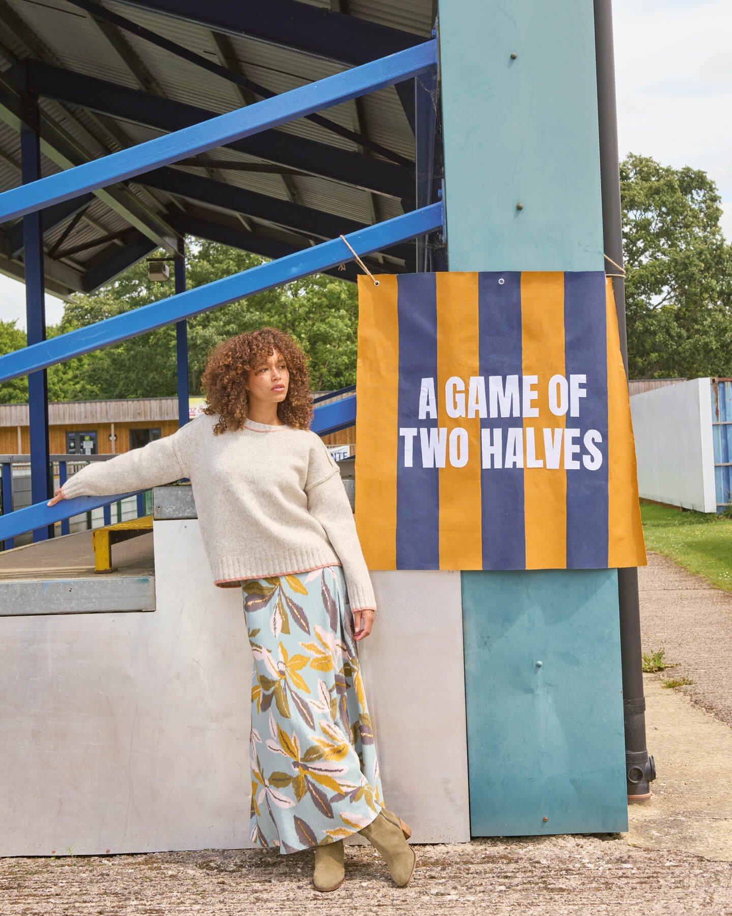 a woman leaning against a wall with a banner hanging from a pole