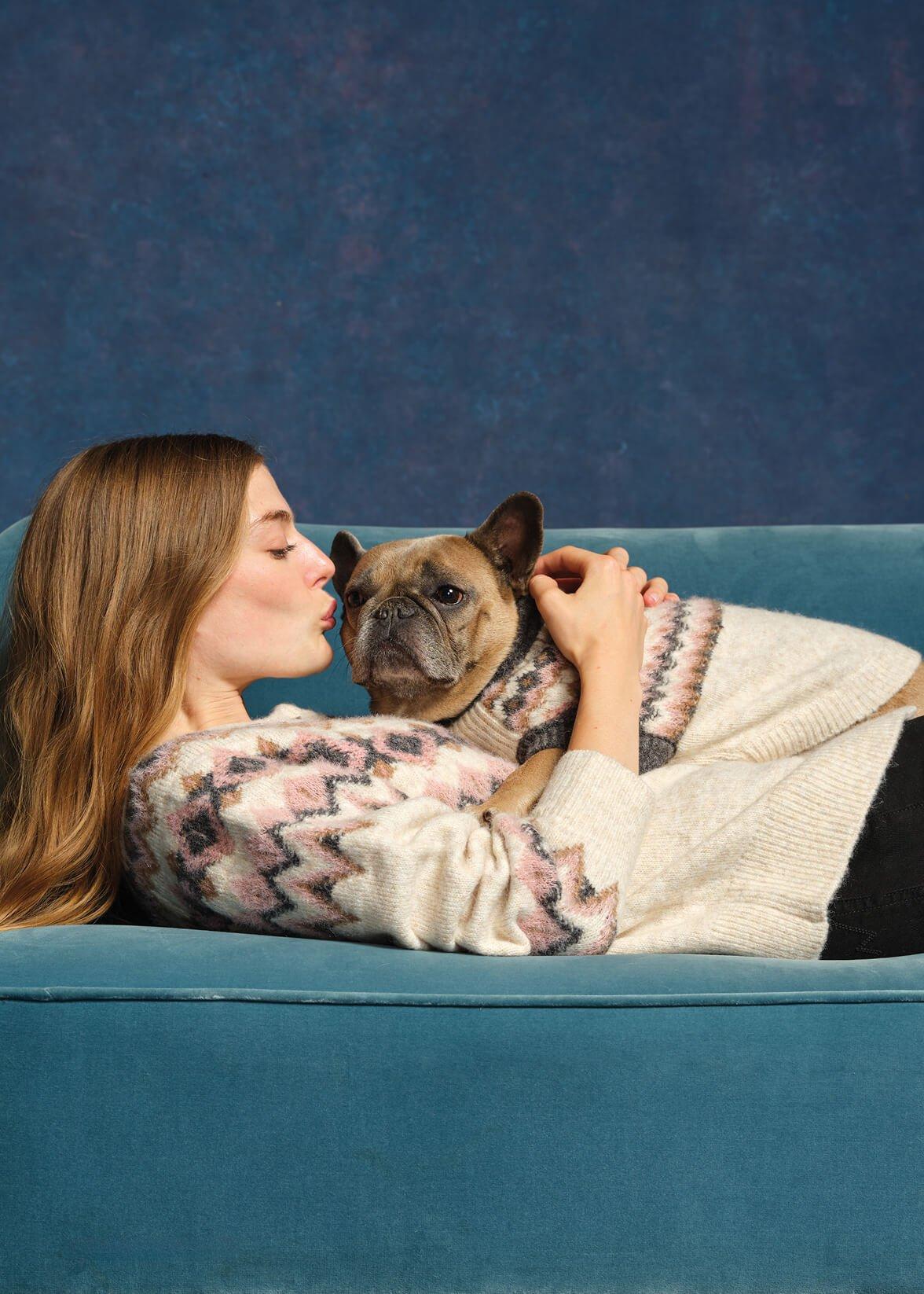 a woman laying on a couch with a dog on her lap