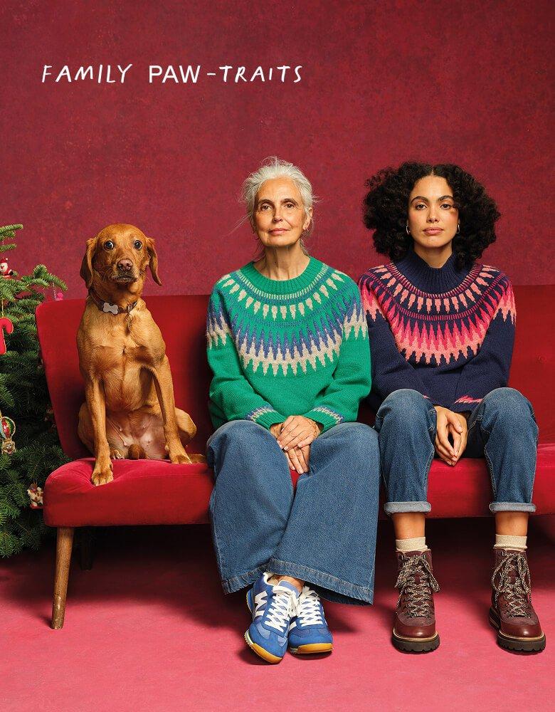 two women and a dog sitting on a red couch 