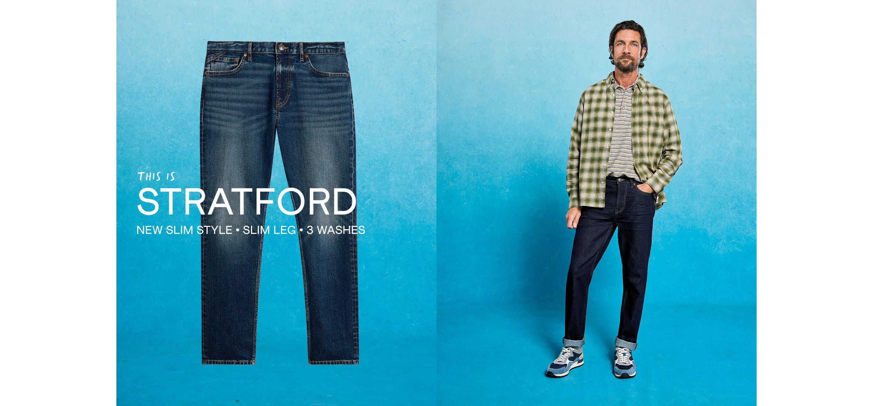 a man in a check shirt and jeans standing next to a blue background