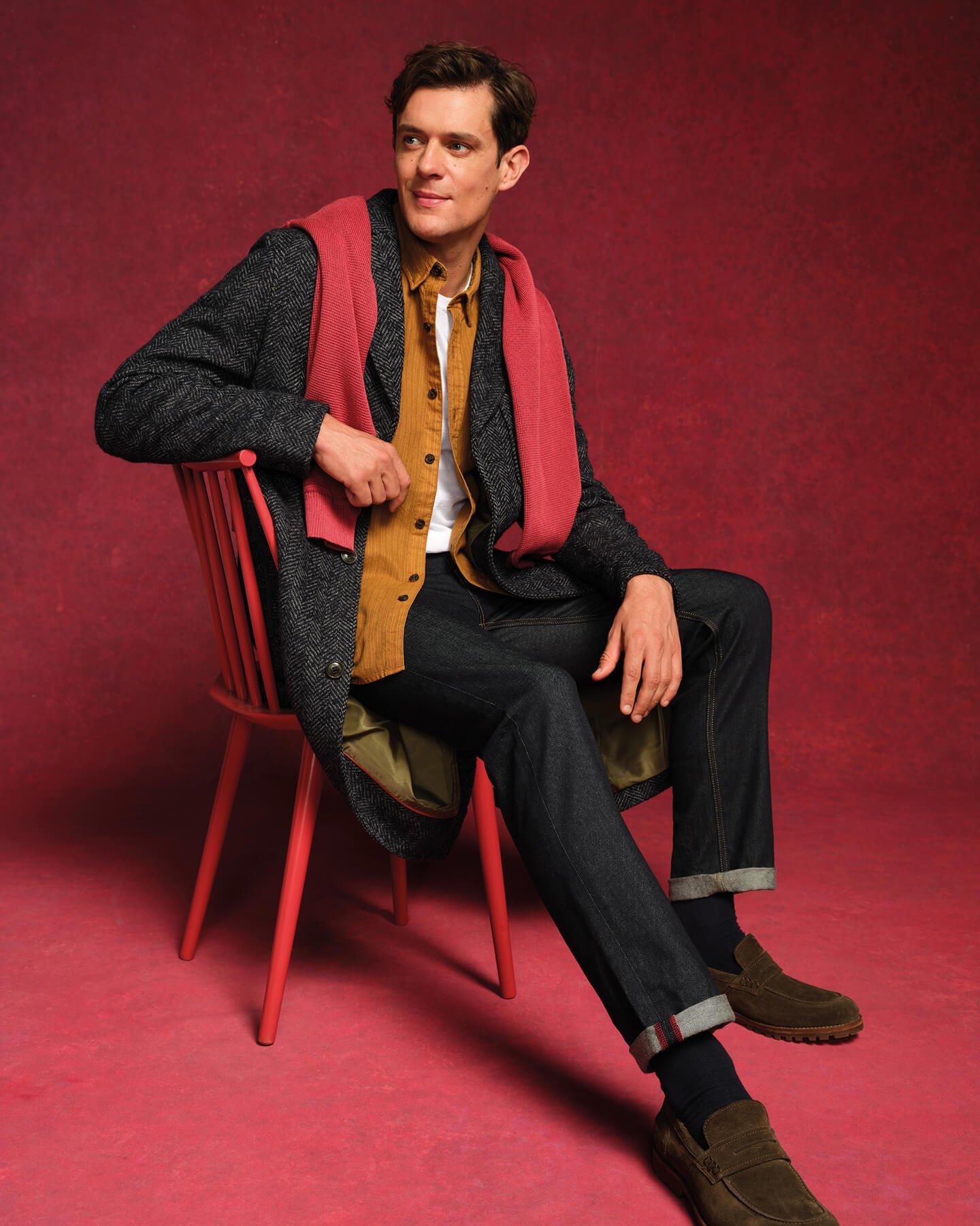 a man sitting on a red chair with a scarf around his neck