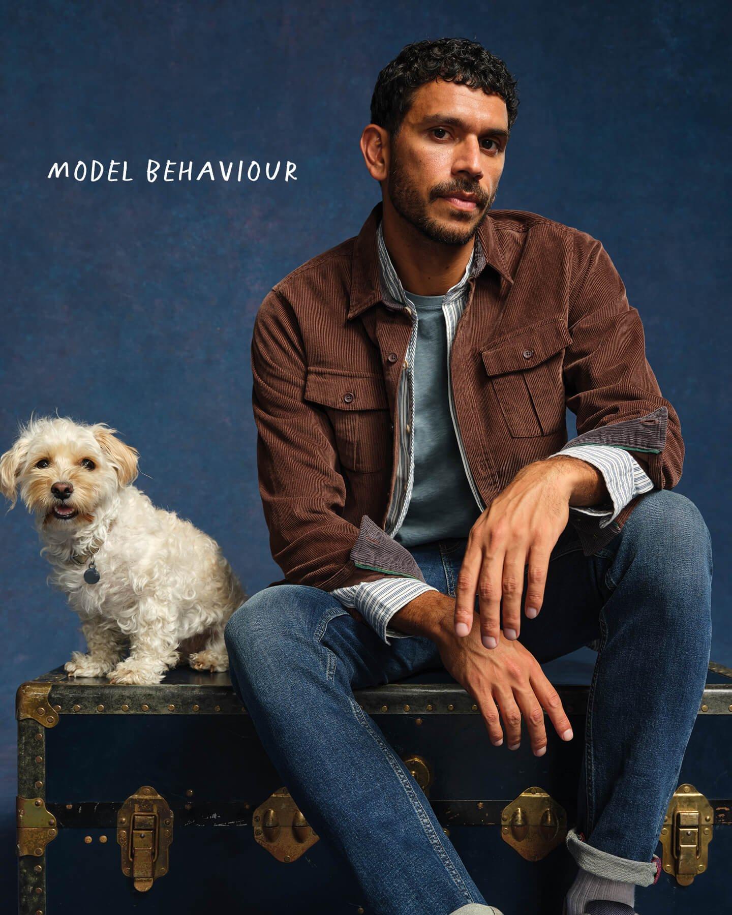 a man sitting on a suitcase with a dog sitting next to him