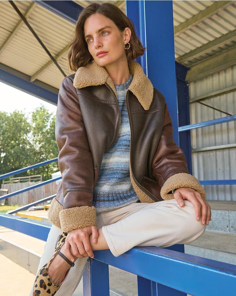a woman in leopard print shoes sitting on a railing