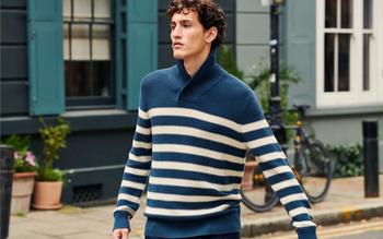 a man in a blue and white striped sweater walking down the street