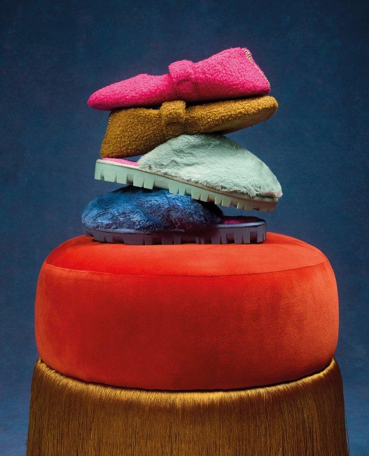 a stack of colorful slippers on a stool with a blue background