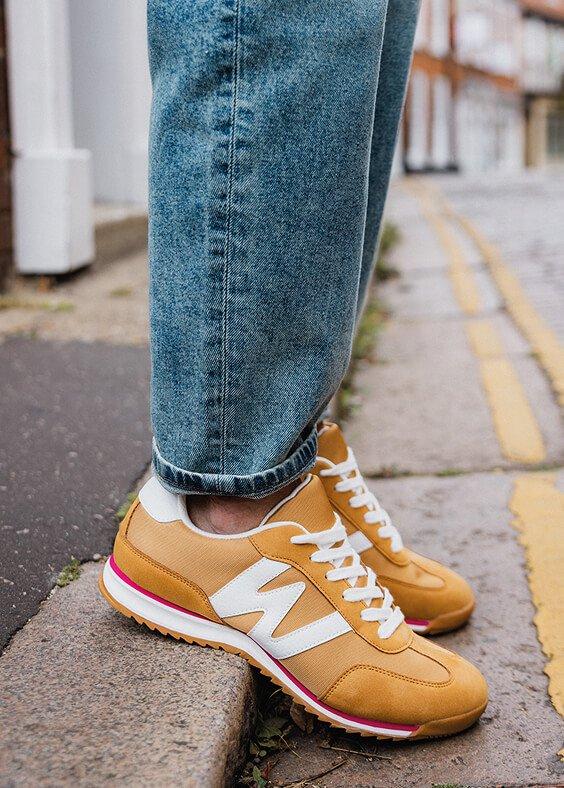 a person wearing yellow sneakers standing on a curb