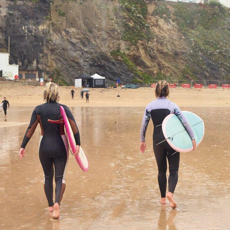 women walking with surfboards