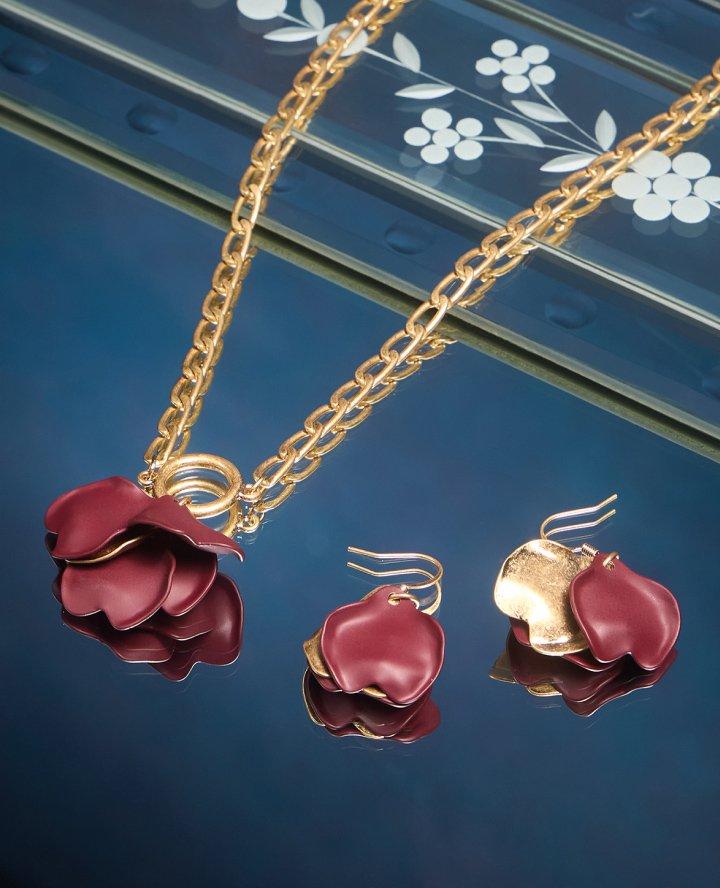 a necklace and earrings with red flowers on a blue background