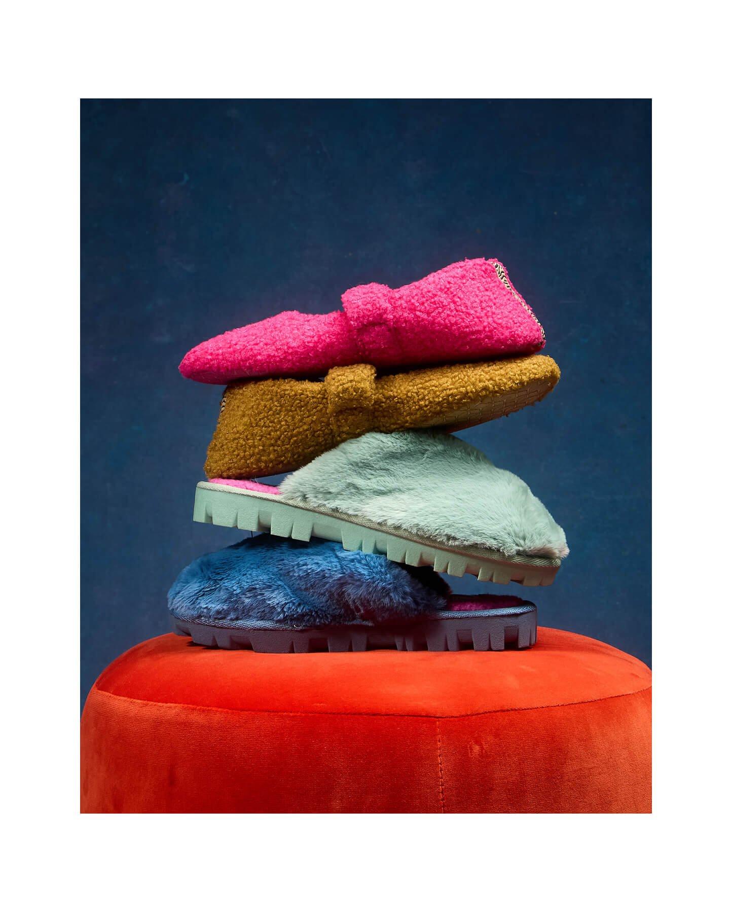 a stack of colorful slippers on top of a red stool