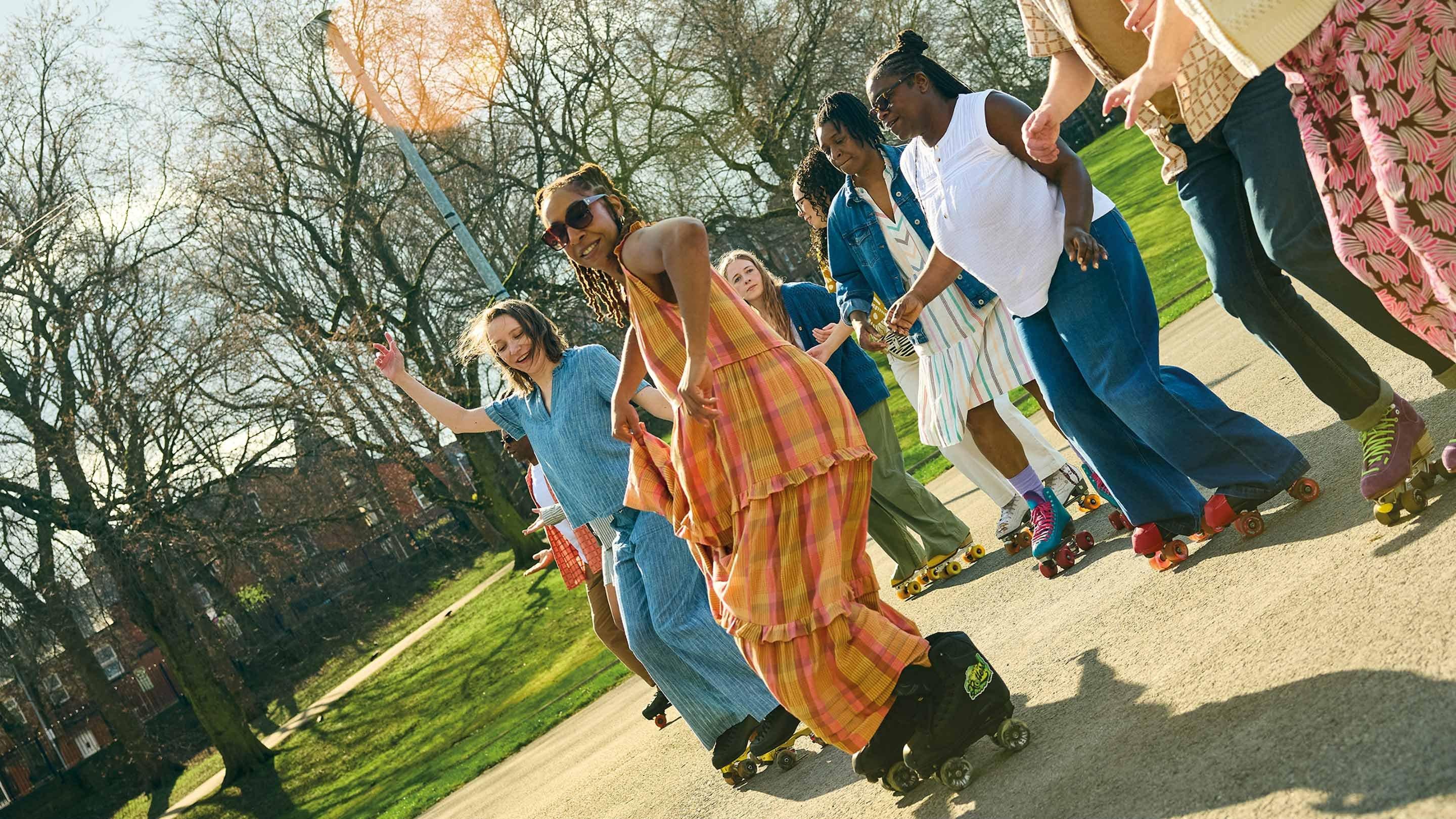a group of people on roller skates in a park with trees