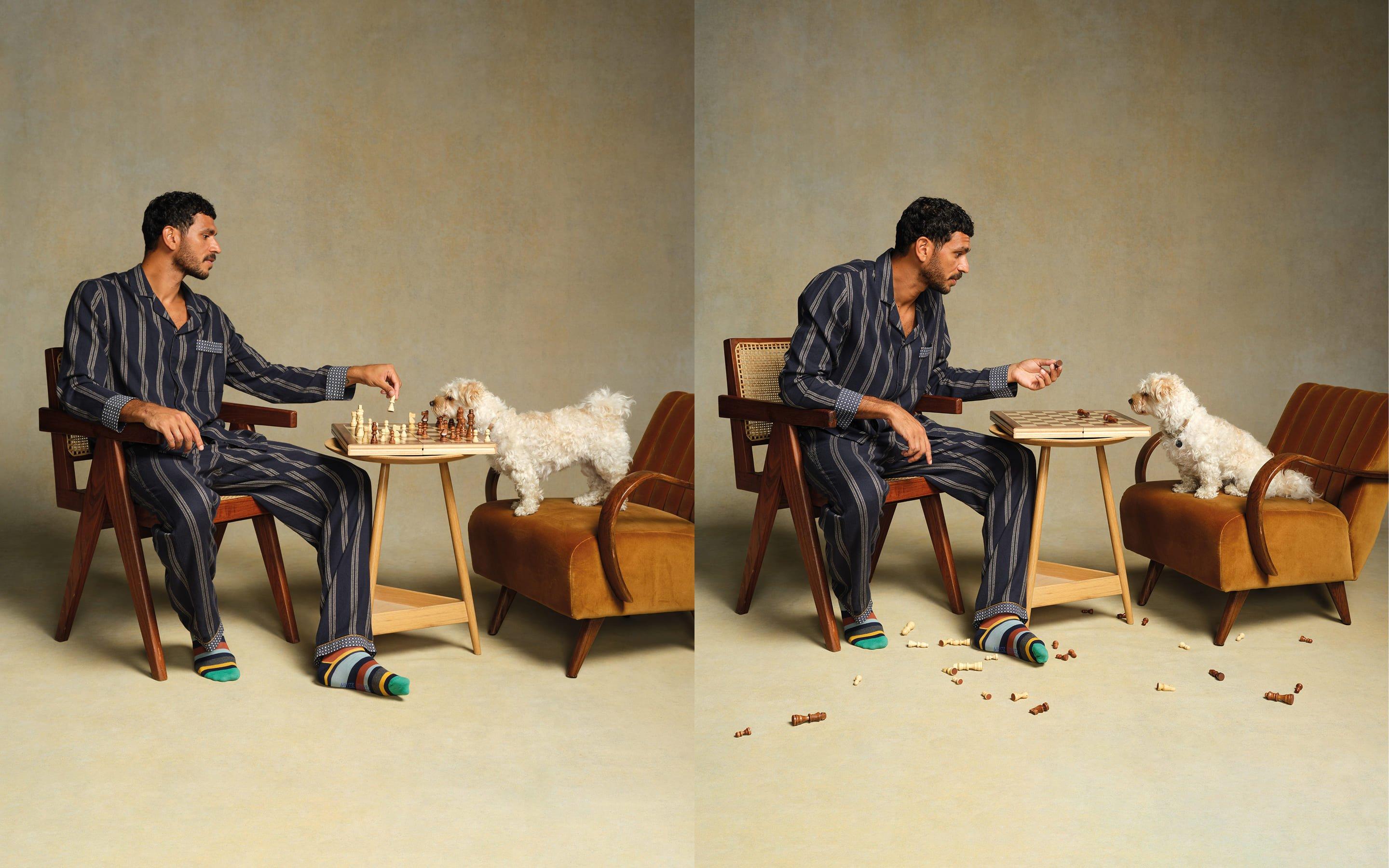 a man sitting in a chair playing chess with a dog