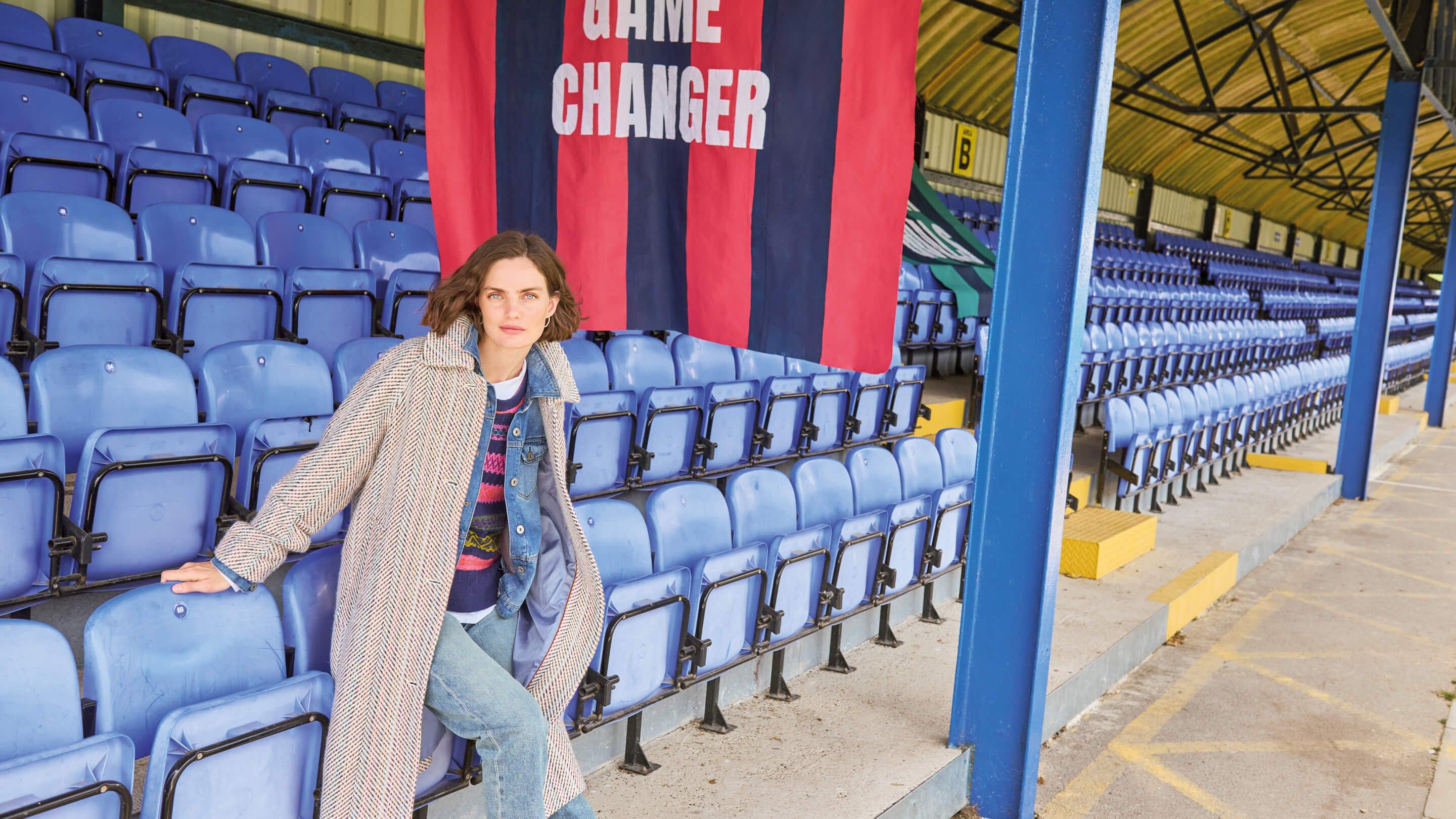 a woman sitting on a blue chair in front of a banner