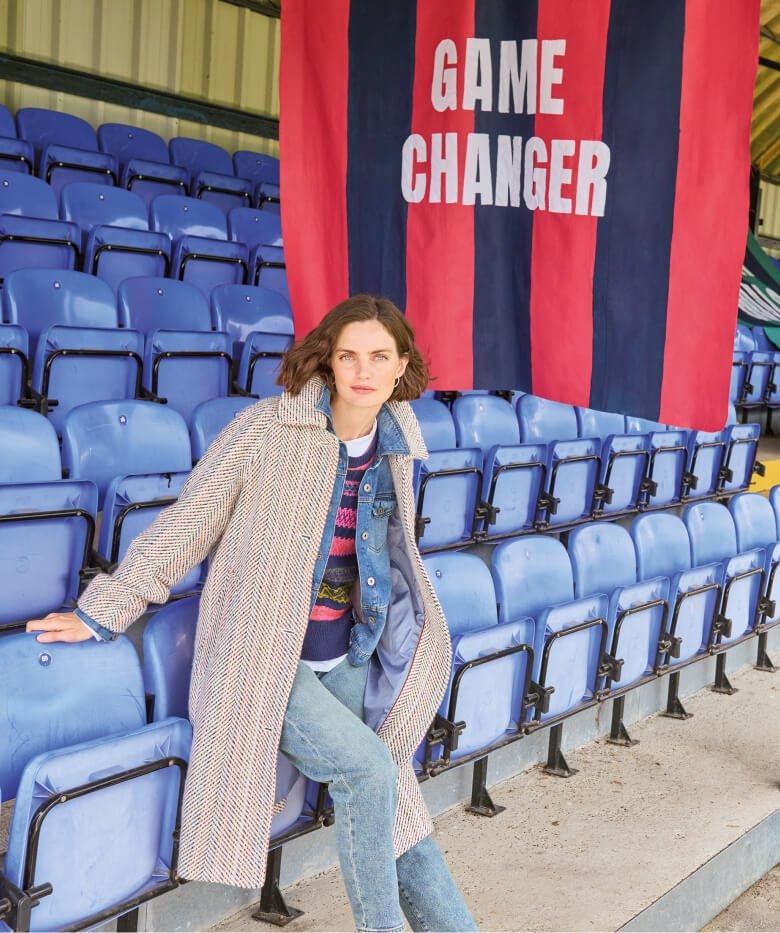 a woman sitting on a bench in front of a banner