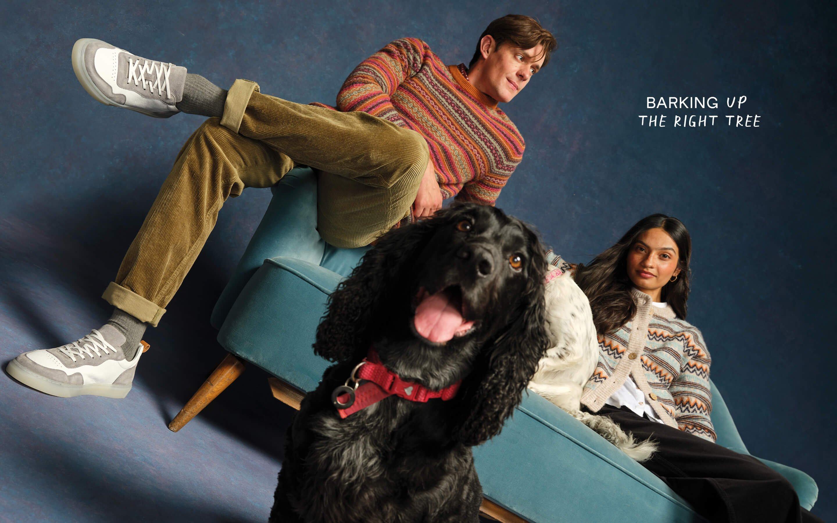 a man and woman sitting on a couch with a dog