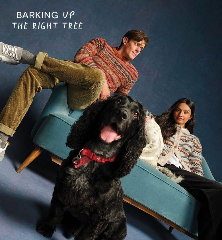 a man and woman sitting on a couch with a dog