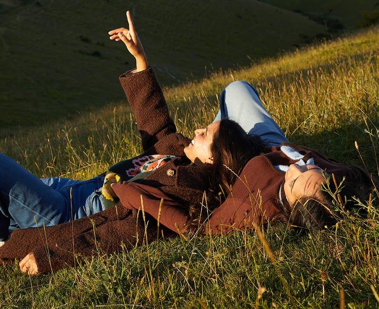 two people laying in a field with one pointing up
