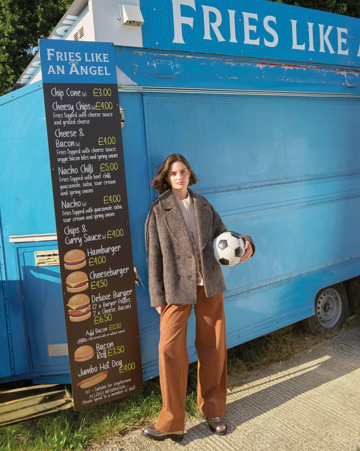 a woman standing in front of a food truck holding a football