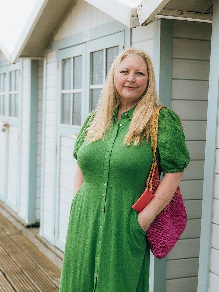 a woman in a dress standing next to a beach hut