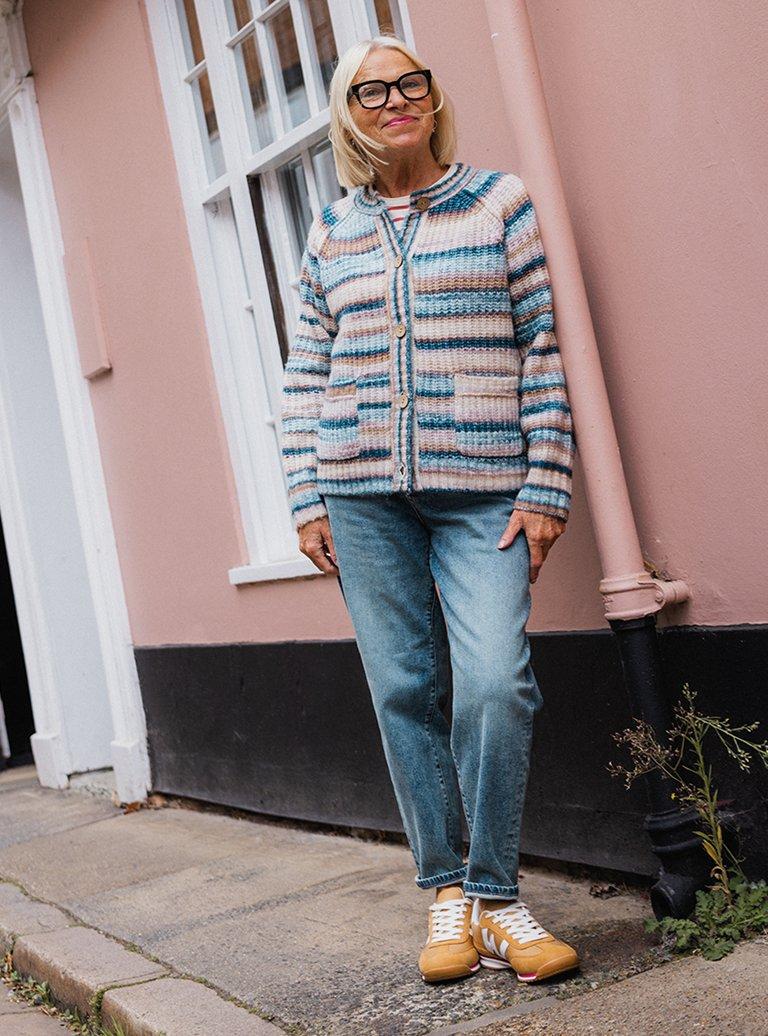 a woman in glasses standing outside a building wearing a knitted cardigan