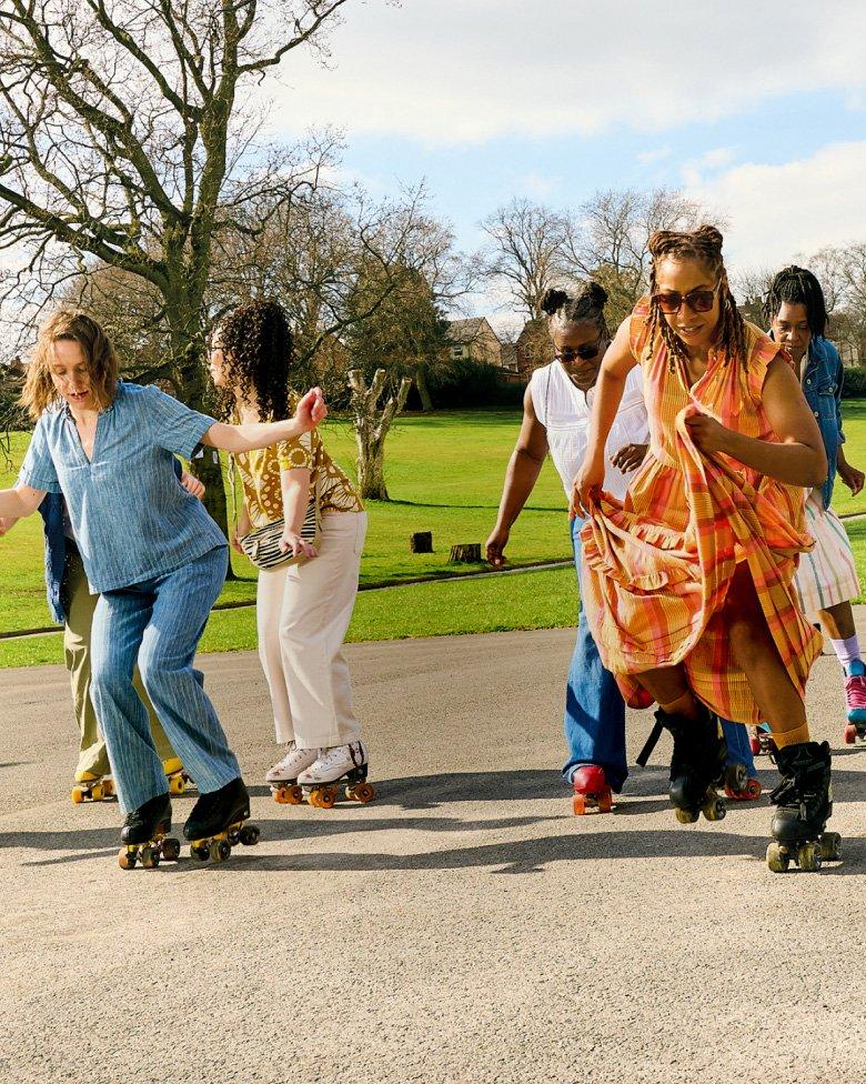 a group of people on roller skates in a park with trees