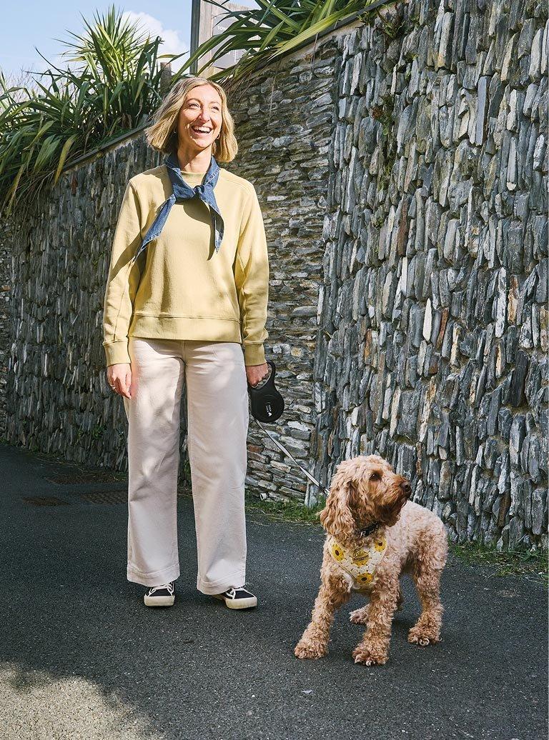 woman in yellow sweater holding a dog on a leash