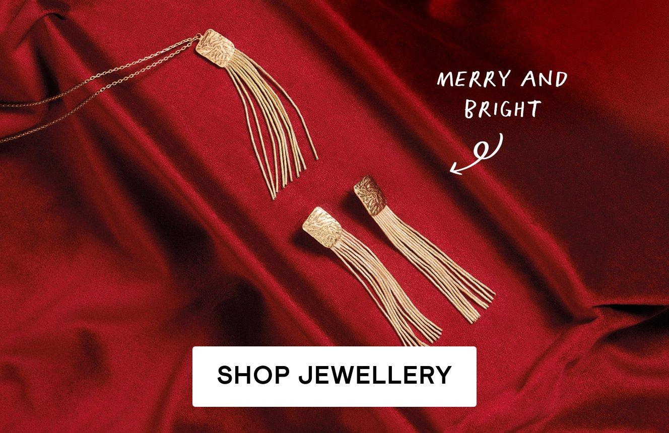 a gold earring and necklace tassle set on a red velvet background. Test is "merry and bright". Click here to shop jewellery