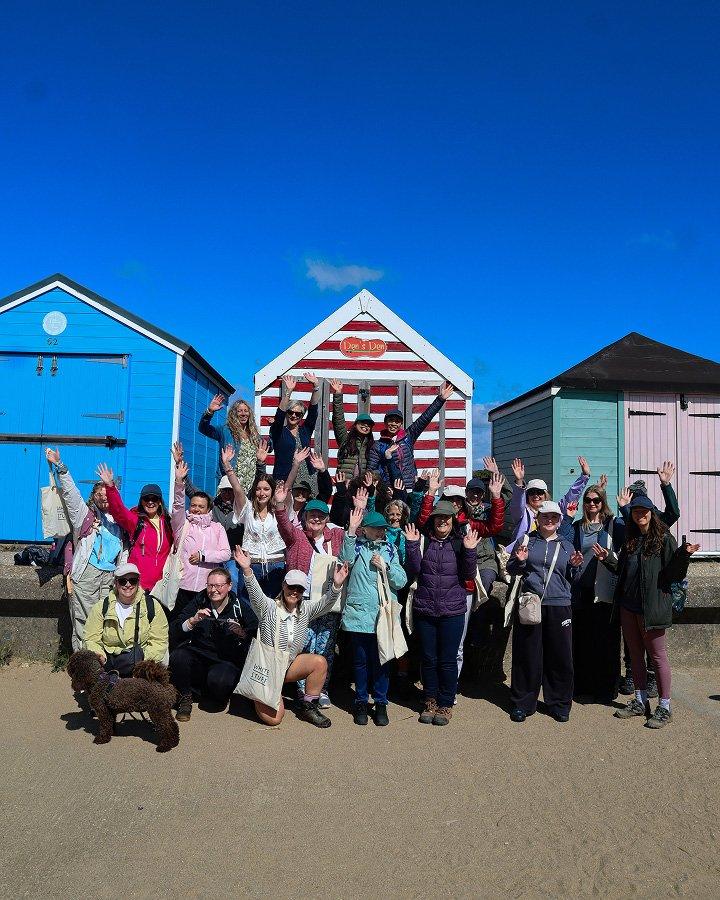 a group of people are posing for a picture in front of beach huts