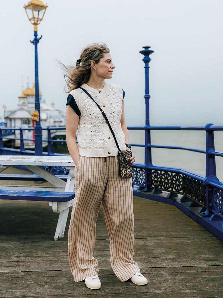 a woman standing on a pier with a bag and a purse in White Stuff clothes