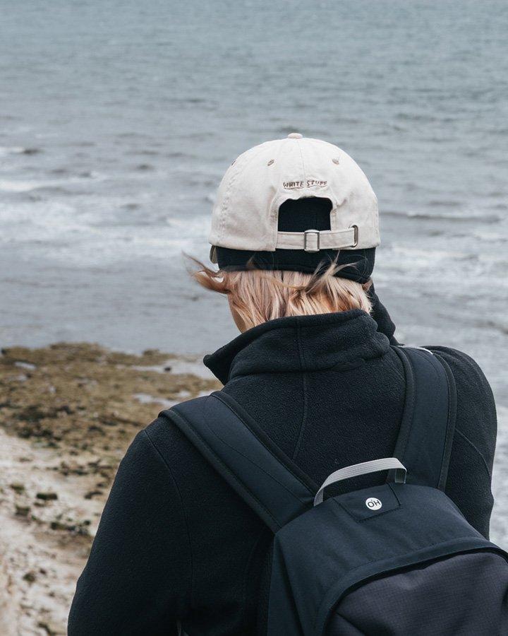 a man with a backpack looking at the ocean from a beach
