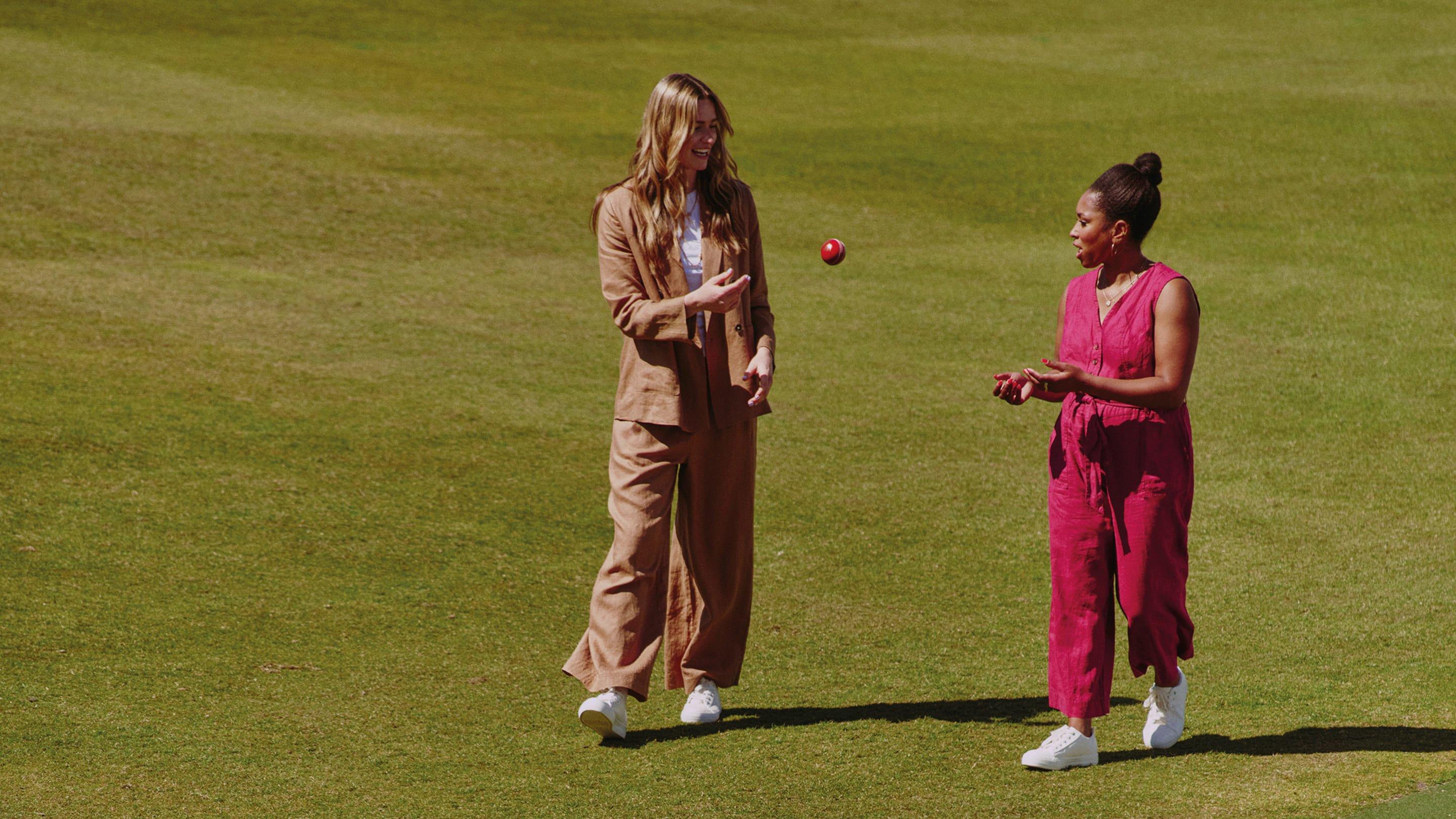 two women are playing a game of cricket on a field
