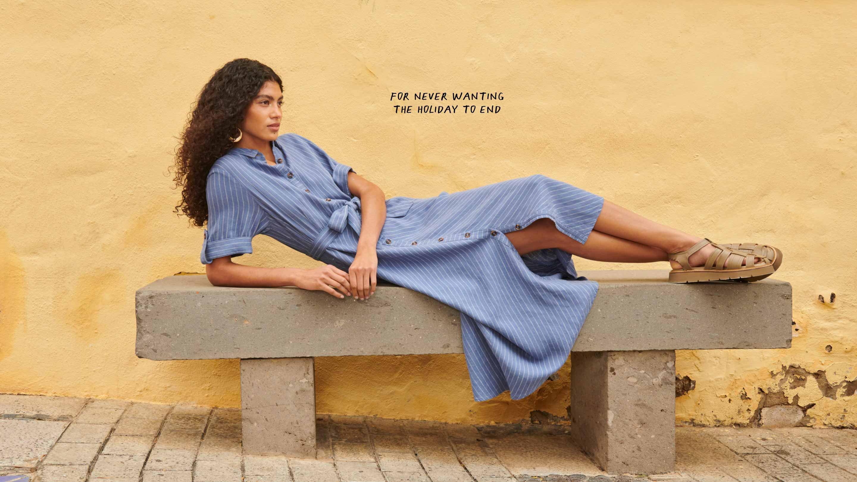 woman in blue linen dress reclining on bench