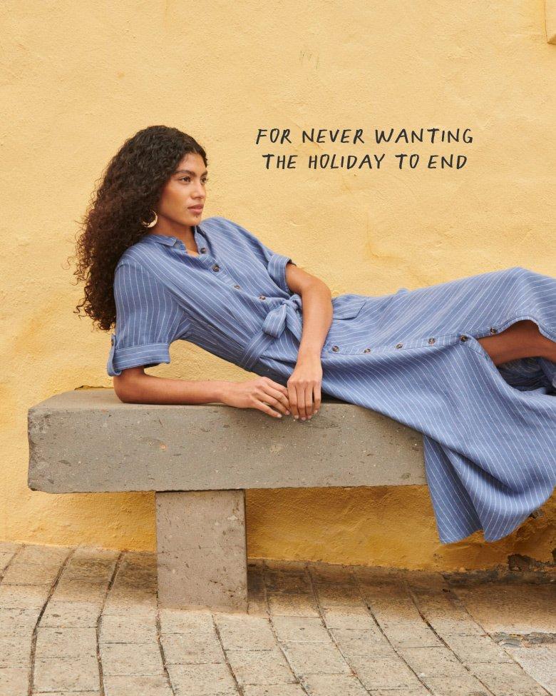 woman in blue linen dress reclining on bench
