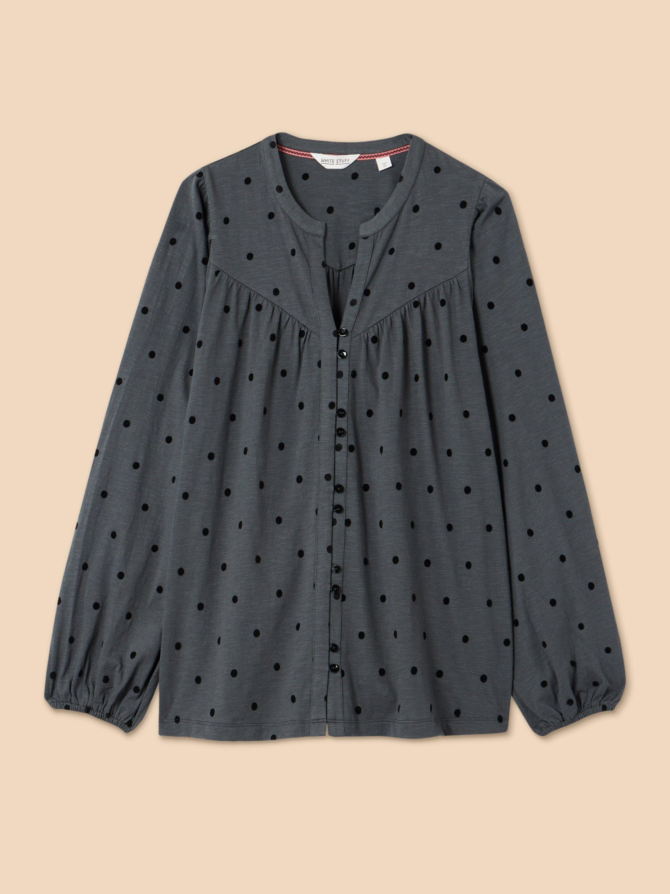 a gray blouse with black dots on it