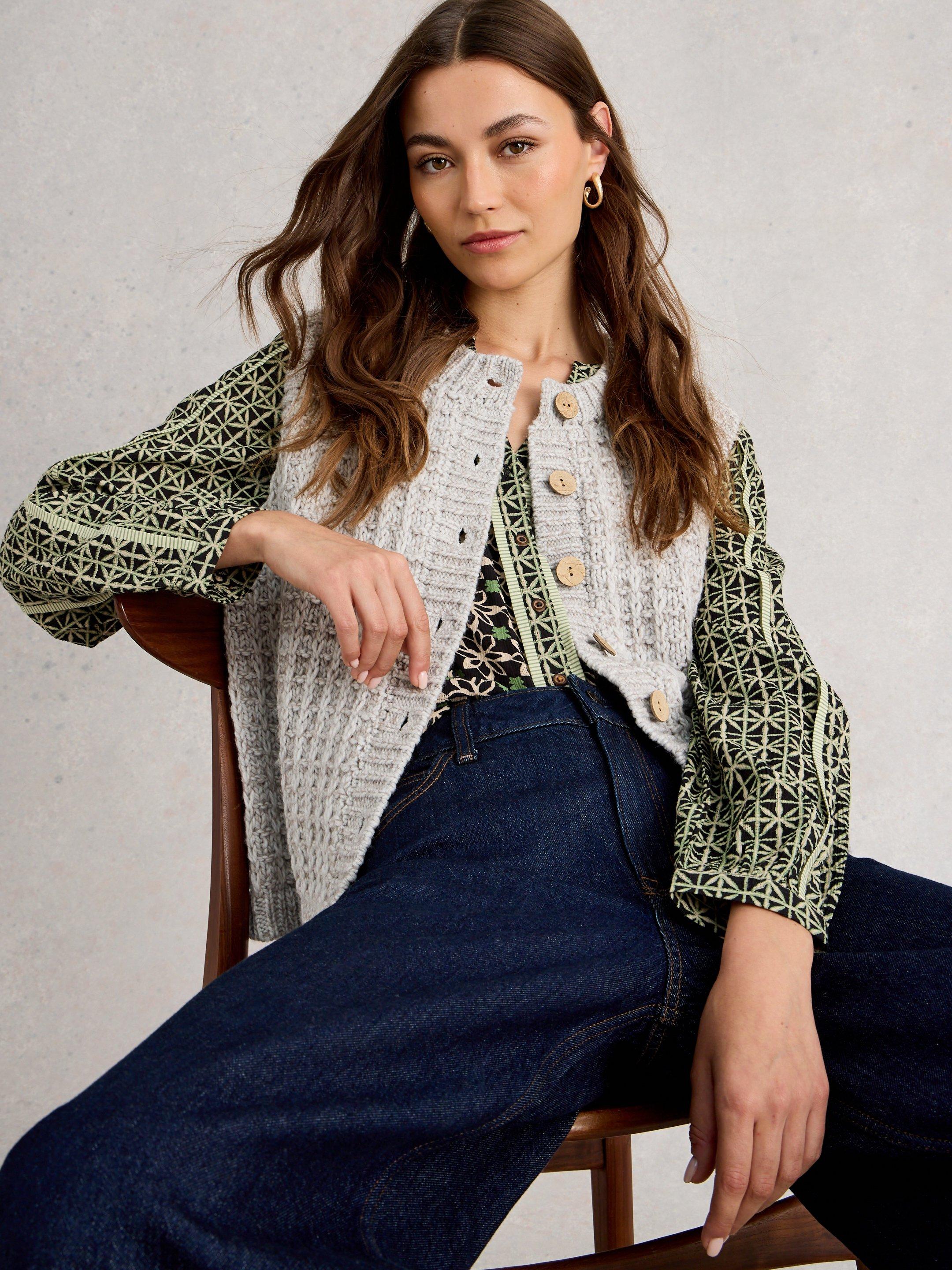 a woman sitting on a chair wearing a sweater and jeans