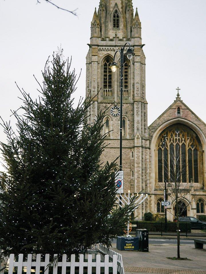 a large church with a tall spire and a small christmas tree