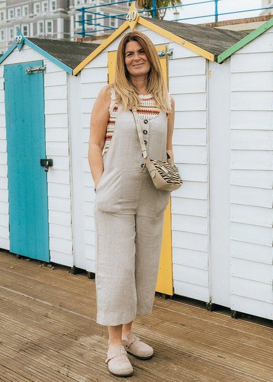 a woman standing in front of a row of beach huts wearing White Stuff
