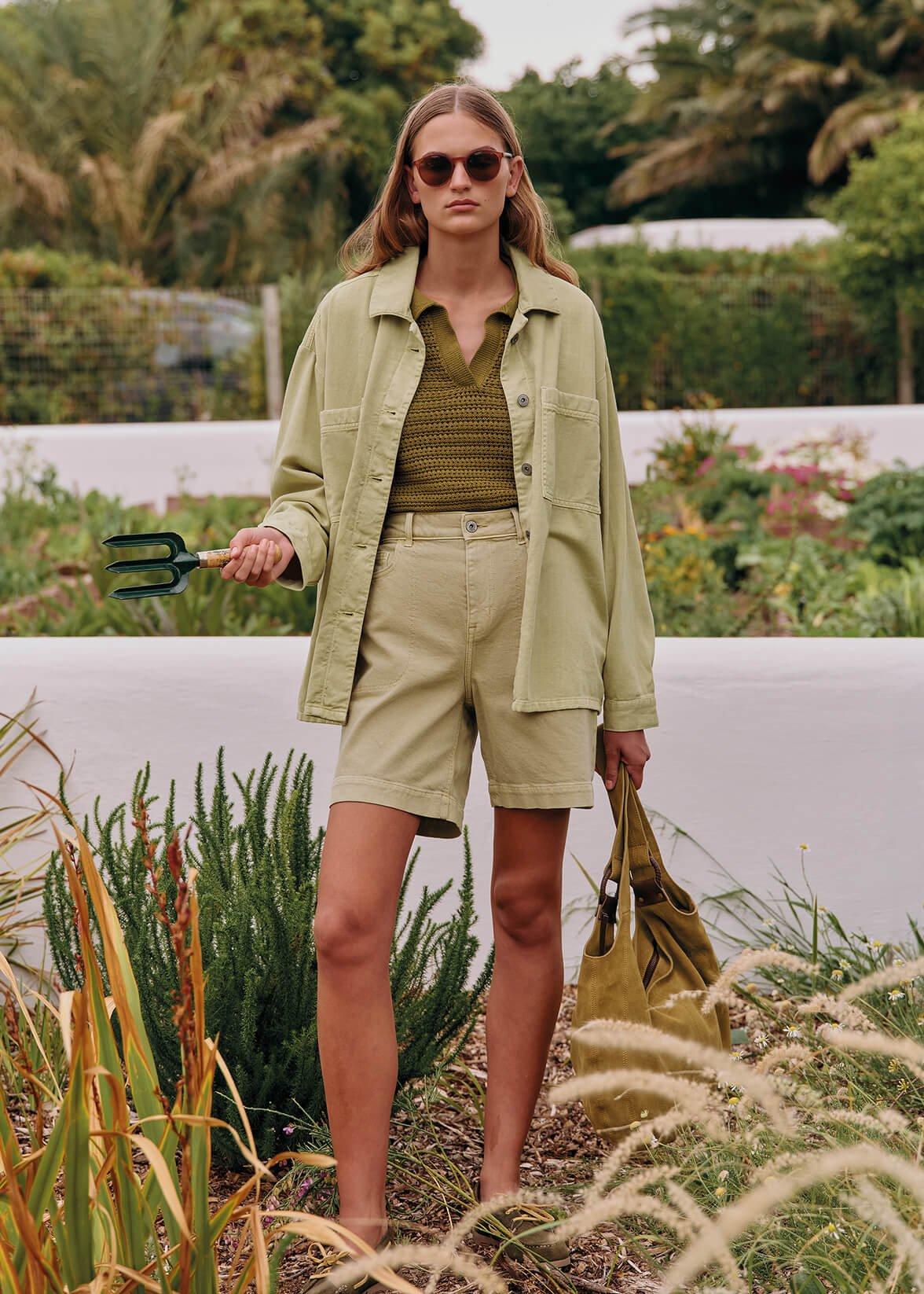 a woman in a tan jacket holding a pair of scissors